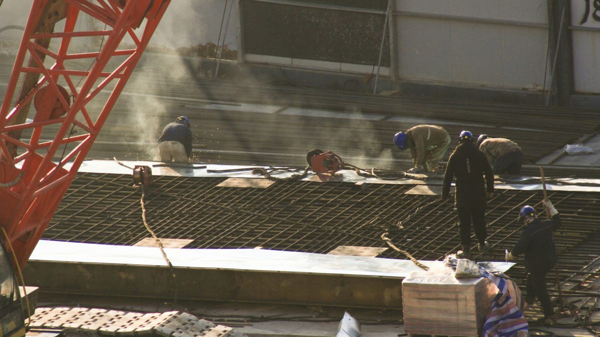 Construction workers in helmets and hi-vis standing on wet ground, wearing S3 boots